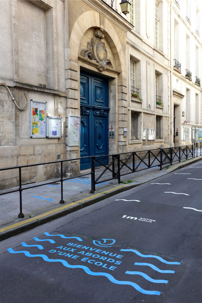 strada davanti ad una scuola francese con segnaletica per il distanziamento